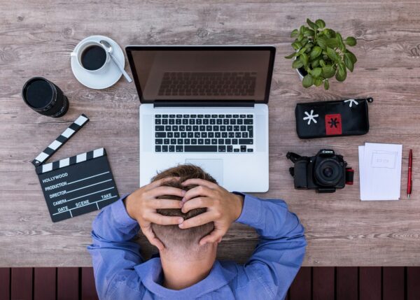 A man is sitting at a desk with a laptop and camera.