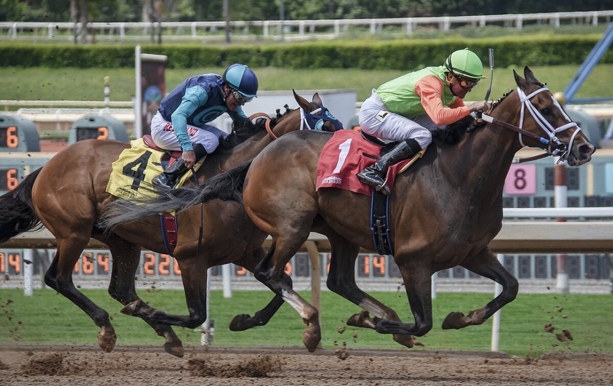 Two jockeys riding horses on a track.