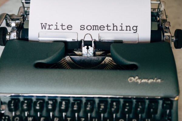 A typewriter with a piece of paper that says write something.